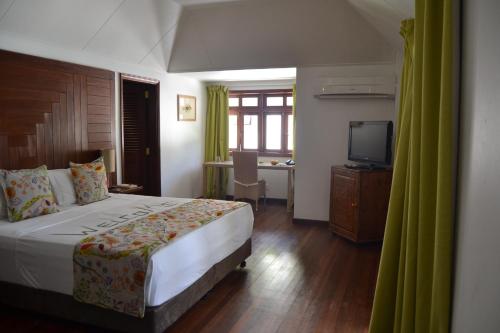 a bedroom with a bed and a desk and a television at La Belle Tortue in Silhouette Island
