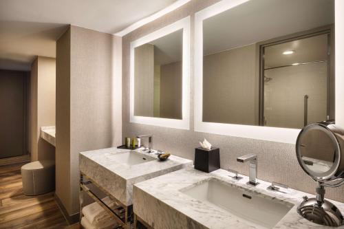 a bathroom with two sinks and a mirror at Hilton Richardson Dallas, TX in Richardson