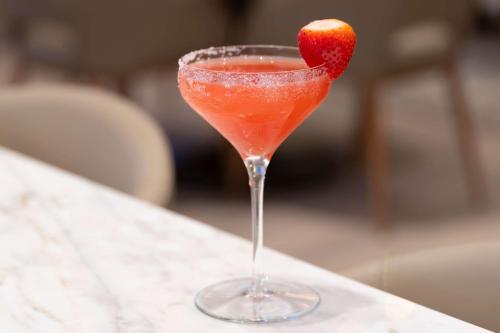 a red drink with a strawberry in a martini glass at Hilton Richardson Dallas, TX in Richardson