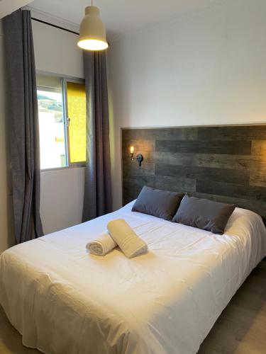 een slaapkamer met een groot bed en 2 handdoeken bij Hostal El Pinar in Montecorto