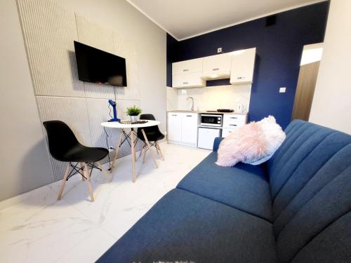 a living room with a blue couch and a kitchen at Mini Apartamenty Poznań in Poznań