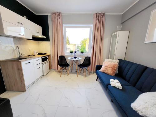 a living room with a blue couch and a kitchen at Mini Apartamenty Poznań in Poznań