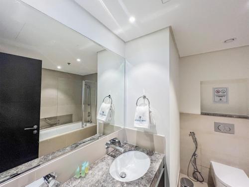 La salle de bains est pourvue d'un lavabo et d'un miroir. dans l'établissement Cosmos Living - Dubai Creek Harbour, à Dubaï