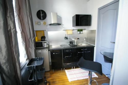 małą kuchnię z czarnymi szafkami i zlewem w obiekcie LA FAYETTE w mieście Reims