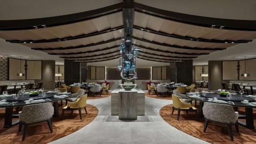 uma sala de jantar com mesas e cadeiras e um lustre em Hilton Lanzhou City Center em Lanzhou