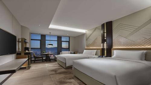een hotelkamer met 2 bedden en een televisie bij Hilton Lanzhou City Center in Lanzhou