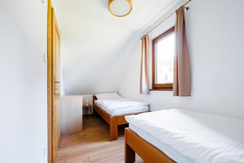 - une chambre avec 2 lits et une fenêtre dans l'établissement Chaty Vážka, à Štiavnické Bane