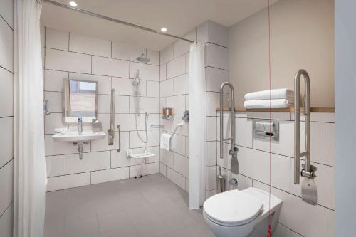 a white bathroom with a toilet and a sink at Hampton By Hilton Tashkent in Tashkent