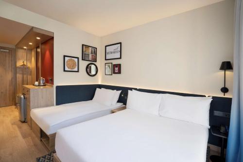 a bedroom with a large white bed with white pillows at Hampton By Hilton Tashkent in Tashkent