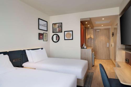 a hotel room with two beds and a flat screen tv at Hampton By Hilton Tashkent in Tashkent