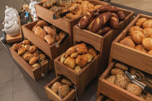 a bunch of different types of breads and pastries in wooden boxes at Hampton by Hilton Konstanz in Konstanz