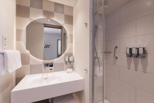 a white bathroom with a sink and a shower at Hampton by Hilton Konstanz in Konstanz