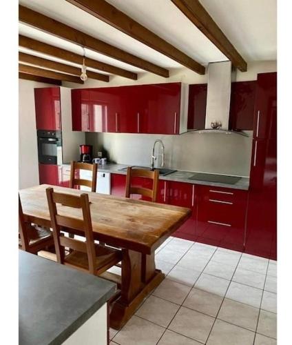 une cuisine avec des placards rouges et une table en bois dans l'établissement Belle longère à 500m de la mer, à Crozon
