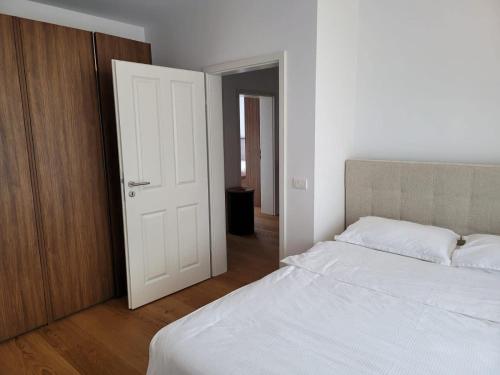 a bedroom with a white bed and a wooden door at Villa QAMA Brezovicë in Štrpce