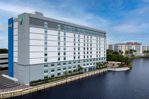 a large white building next to a body of water at Home2 Suites By Hilton Miami Airport South Blue Lagoon in Miami