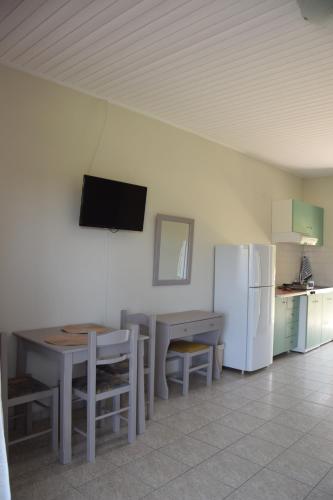 a kitchen with a table and a white refrigerator at Odysseas rooms in Kalón Nerón