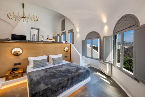 ein Schlafzimmer mit einem großen Bett und großen Fenstern in der Unterkunft Eteoro Suites in Imerovigli