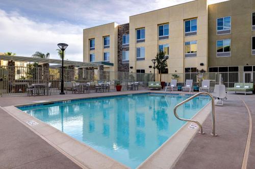 a swimming pool at a hotel with chairs and tables at Hilton Garden Inn Temecula in Temecula