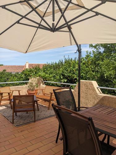un patio avec tables, chaises et un parasol dans l'établissement Gîte Botanica, à Gignac