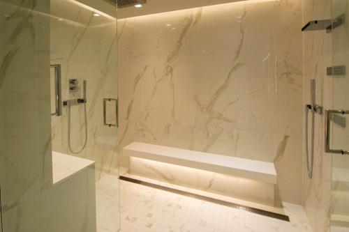 een witte badkamer met een douche en een glazen deur bij The Benson Portland, Curio Collection by Hilton in Portland