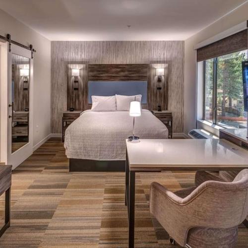 a bedroom with a bed and a table and chairs at Hampton Inn & Suites South Lake Tahoe in South Lake Tahoe