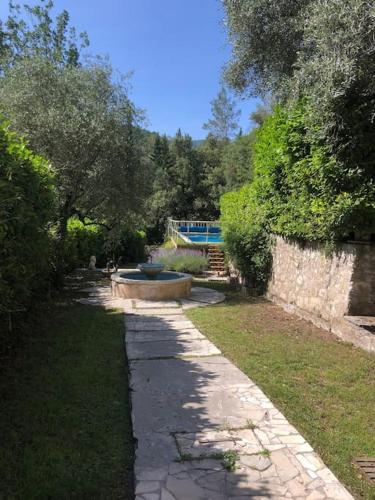 a stone path in a garden with a bench and trees at Villa piscine 30 minutes de Nice in Le Broc