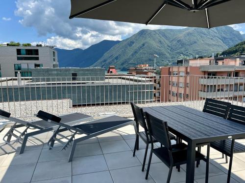 a table and chairs on a balcony with mountains at Lakeside Attic in Lugano