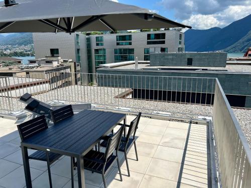 a table and chairs on a balcony with an umbrella at Lakeside Attic in Lugano