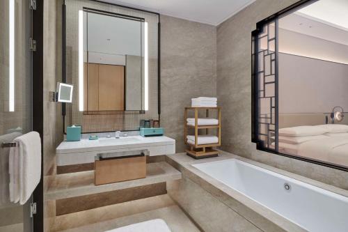 a bathroom with a tub and a sink and a bed at Hilton Suzhou Wuzhong in Suzhou