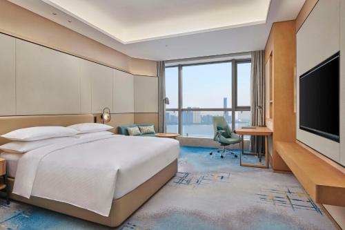 a hotel room with a bed and a flat screen tv at Hilton Suzhou Wuzhong in Suzhou