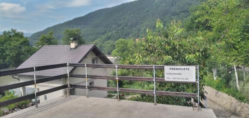 a house with a sign in front of a mountain at Prenoćište na Drini Foča in Foča