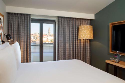 a hotel room with a large bed and a window at Se Catedral Hotel Porto, Tapestry Collection By Hilton in Porto