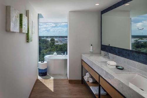 a bathroom with a tub and a sink and a mirror at Hilton Garden Inn Cancun Airport in Cancún