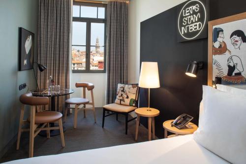 a hotel room with a bed and a table and chairs at Se Catedral Hotel Porto, Tapestry Collection By Hilton in Porto