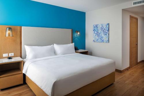 a large white bed in a room with a blue wall at Hilton Garden Inn Cancun Airport in Cancún