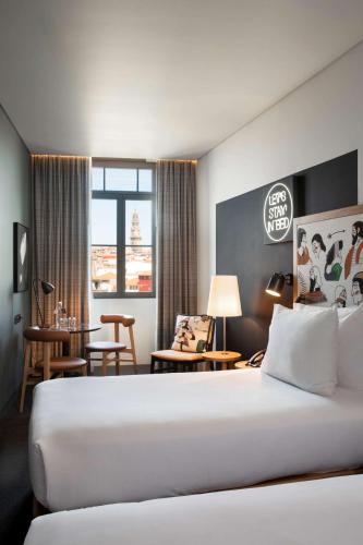 a hotel room with a large bed and a table at Se Catedral Hotel Porto, Tapestry Collection By Hilton in Porto