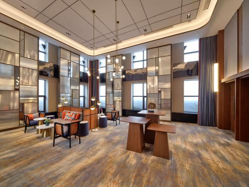 a lobby with tables and chairs and windows at Hilton Garden Inn Jinzhou Central Street in Jinzhou