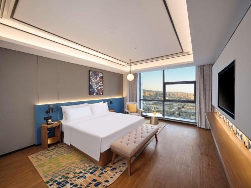 a bedroom with a large white bed and a large window at Hilton Garden Inn Jinzhou Central Street in Jinzhou