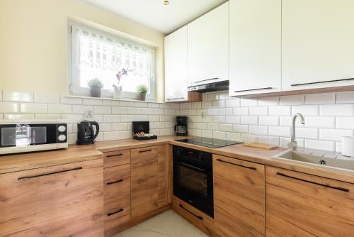 a kitchen with wooden cabinets and a sink and a microwave at Apartament Widok Zakopane in Zakopane