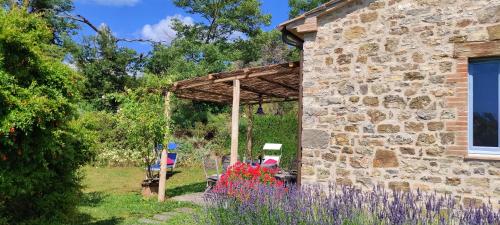 a stone house with a garden with purple flowers at Podere Sant'Angelo in Roccalbegna