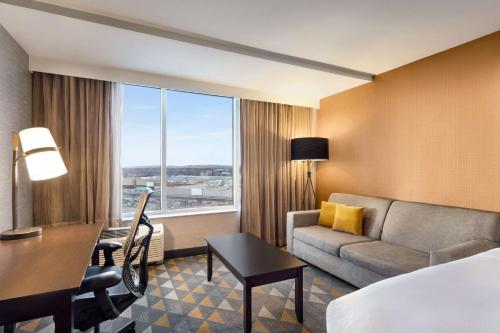 a hotel room with a bed and a couch and a desk at Doubletree By Hilton Pointe Claire Montreal Airport West in Pointe-Claire