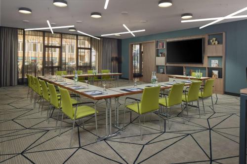 a conference room with a long table and green chairs at DoubleTree by Hilton Hannover Schweizerhof in Hannover