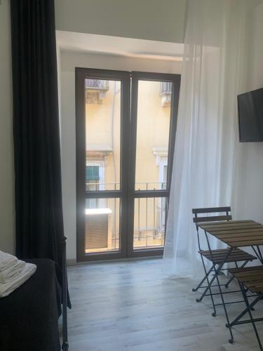 Habitación con ventana grande, mesa y sillas. en Loft Home Sweet Home en Catania