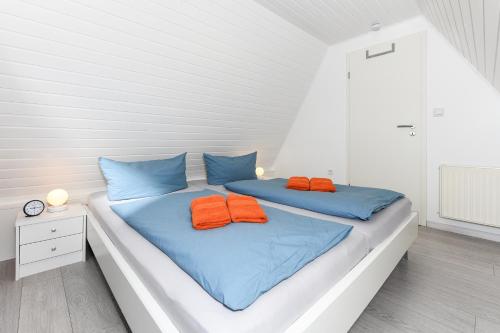 ein Bett mit zwei orangenen Kissen darüber in der Unterkunft Ferienhaus Daniela in Neuharlingersiel