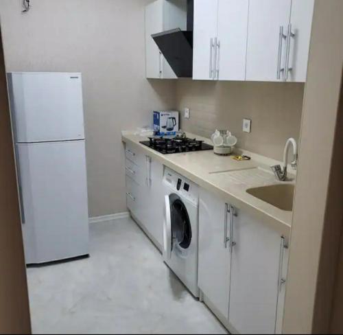 a white kitchen with a washing machine and a sink at Sweet home in Baku