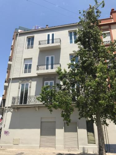 un edificio de apartamentos con un árbol delante de él en Belmar Apartments en Valencia