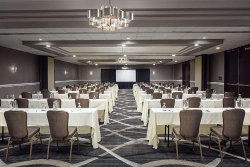 a conference room with white tables and chairs and a screen at DoubleTree by Hilton Cherry Hill Philadelphia in Cherry Hill