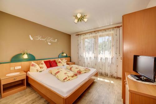 um pequeno quarto com uma cama e uma televisão em Appartement Thanei em Burgusio