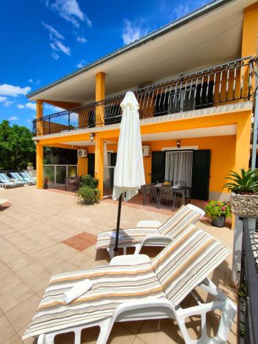 a group of lounge chairs and an umbrella on a patio at VILLA JURAS in Podstrana
