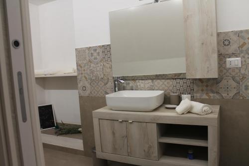 ein Bad mit einem Waschbecken und einem Spiegel in der Unterkunft Casetta Pisanelli 25 in Mottola